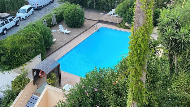 Área residencial com piscina, veículos estacionados e vegetação exuberante.
