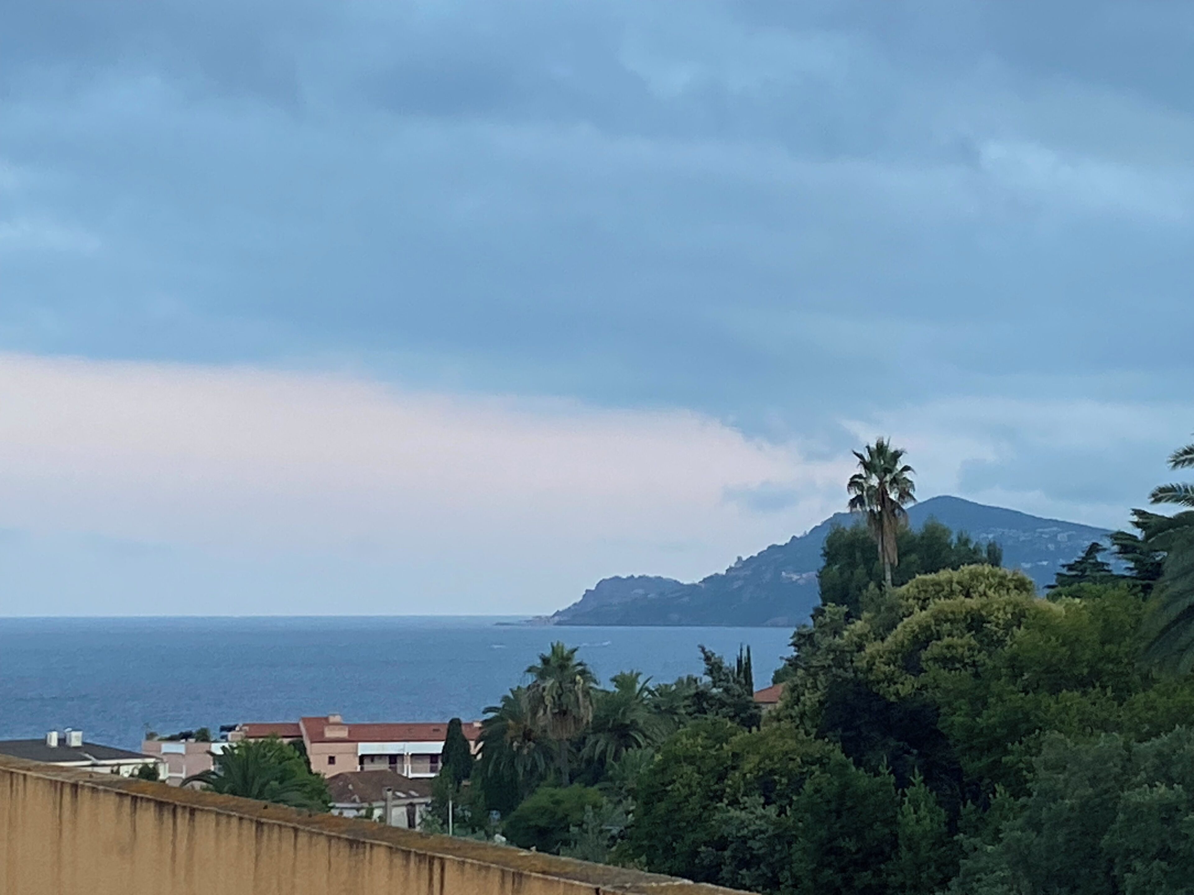 Paisagem costeira com montanha, casas e vegetação densa.