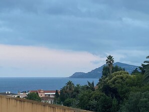 A coastal landscape with a mountain, houses, and dense greenery. - Air-conditioned apartment for 5 people. Patio. Pool. Beach: 20-minute walk (Cannes)