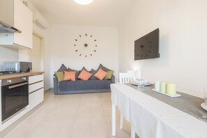 A modern kitchen with a built-in oven and a dining area with a table set for two. - ErKaNi Dimora Sorrento – Contemporary 1-Bedroom Apartment in Downtown Sorrento (Sorrento)