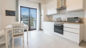 A modern kitchen with white cabinetry, a built-in oven, and a microwave. - ErKaNi Dimora Sorrento – Contemporary 1-Bedroom Apartment in Downtown Sorrento (Sorrento)
