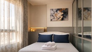 A hotel room with a bed, a painting on the wall, and a nightstand with candles. - S&G Beachfront Serviced 1-br, Step to Tops and 7-11 (Pattaya)