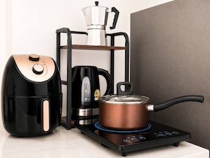 A kitchen with a coffee maker, a kettle, and a pot on an induction cooktop. - S&G Beachfront Serviced 1-br, Step to Tops and 7-11 (Pattaya)