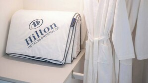 A neatly folded white pillow with the Hilton Hotels & Resorts logo on a white surface, next to a white bathrobe hanging on a rack. - S&G Beachfront Serviced 1-br, Step to Tops and 7-11 (Pattaya)