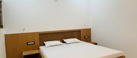 A bedroom with a wooden bed, a nightstand, a ceiling fan, and a light switch on the wall.