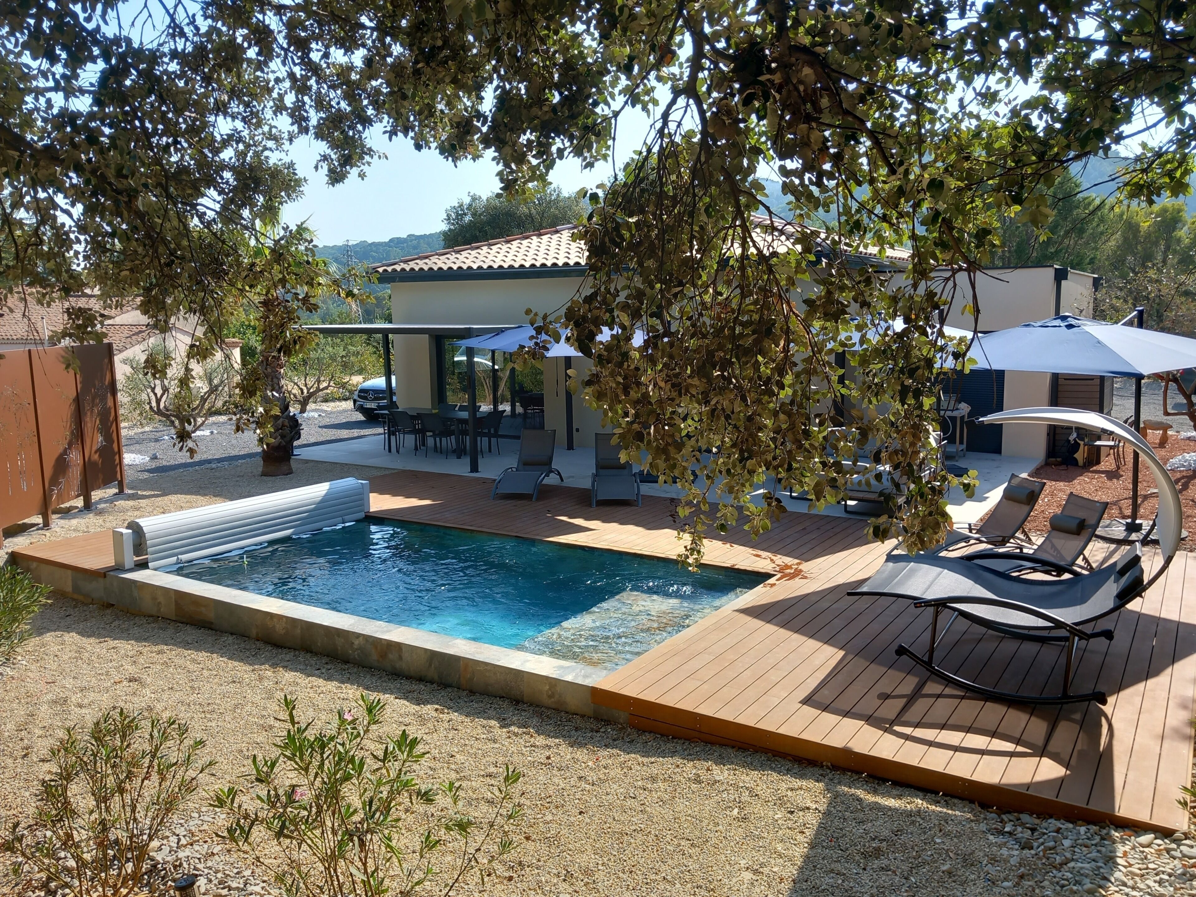 Une piscine avec une terrasse en bois, des chaises longues et des parasols.