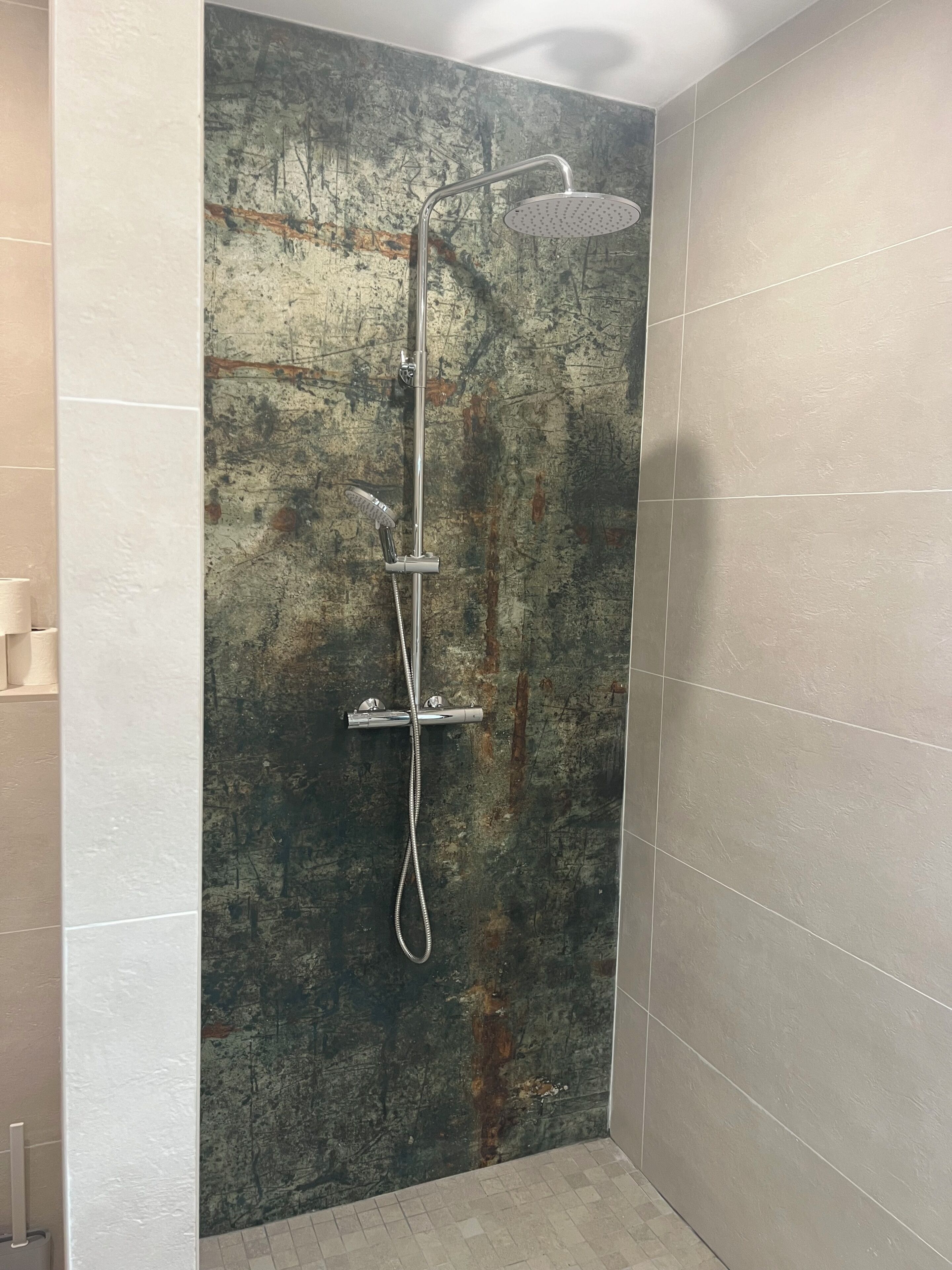 Une douche au design moderne, un mur à texture et un sol carrelé.