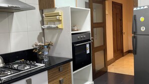A modern kitchen with a gas stove, oven, and refrigerator. - luxuary 3-bedroom apartment with AC in adorable Mohammédia (Mohammédia)