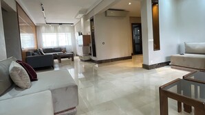 A spacious living area with a high ceiling, a sofa set, a coffee table, and a dining table. - luxuary 3-bedroom apartment with AC in adorable Mohammédia (Mohammédia)