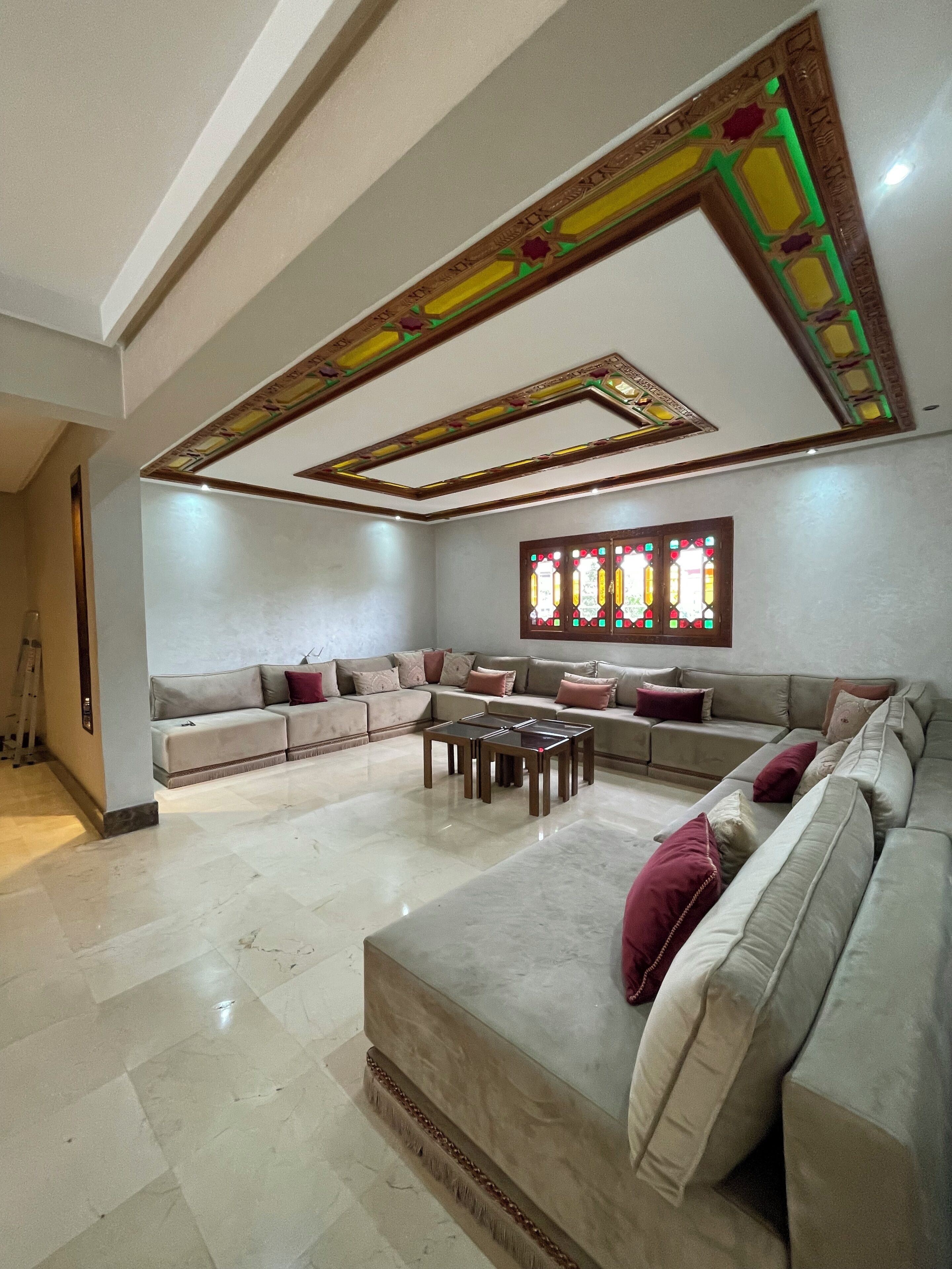 A spacious living room with a sectional sofa, a coffee table, and a decorative ceiling with stained glass.