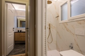Ein Badezimmer mit Dusche, Toilette, Waschbecken und Spiegel.