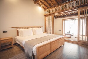 Une chambre avec un lit en bois, des tables de chevet, une vue à travers un paravent japonais et un petit balcon.
