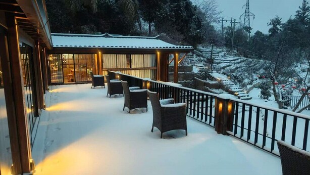 A snow-covered outdoor area with seating and a view of a snowy landscape. - Shanyunjian Hotel Co. Ltd. (Shiyan)