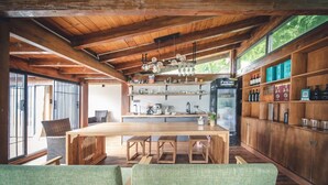 A wooden interior with a central table, chairs, a refrigerator, shelves with bottles, and a window. - Shanyunjian Hotel Co. Ltd. (Shiyan)