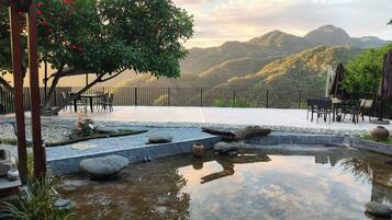 A serene outdoor patio area with a stone water feature, seating arrangements, and a view of distant hills.