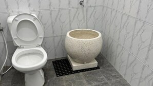 A bathroom with a toilet, a large stone basin, and grey marble tiles. - Cozzy Joeragan Homestay (Turi)