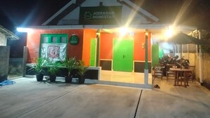 A building with a sign reading 'JOERAGAN HOMESTAY' and a covered outdoor seating area. - Cozzy Joeragan Homestay (Turi)