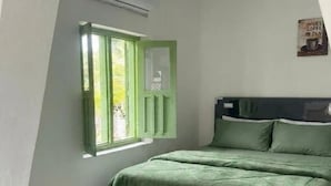 A bedroom with a bed, a window with green shutters, and a wall-mounted air conditioning unit. - Cozzy Joeragan Homestay (Turi)