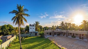 A building with multiple rooms, a courtyard, and palm trees. - Modern room in the center of Vilanculos (AC-TV), 5 minutes from the beach (Vilankulo)