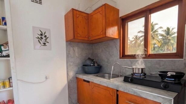 A compact kitchen with a gas stove, a sink, and wooden cabinets. - Modern room in the center of Vilanculos (AC-TV), 5 minutes from the beach (Vilankulo)