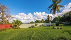 A well-maintained lawn with palm trees and a red fence. - Modern room in the center of Vilanculos (AC-TV), 5 minutes from the beach (Vilankulo)