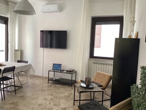 A living room with a TV, a dining table, chairs, a coffee table, and a window with blinds. - Well. St. House | Downtown - 5-minute walk to the beach - 3 bedrooms (Pescara)