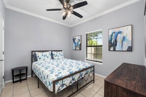 A bedroom with a bed, a ceiling fan, a window with blinds, and two framed artworks on the wall. - The C2 Gateway to Starbase (Brownsville)