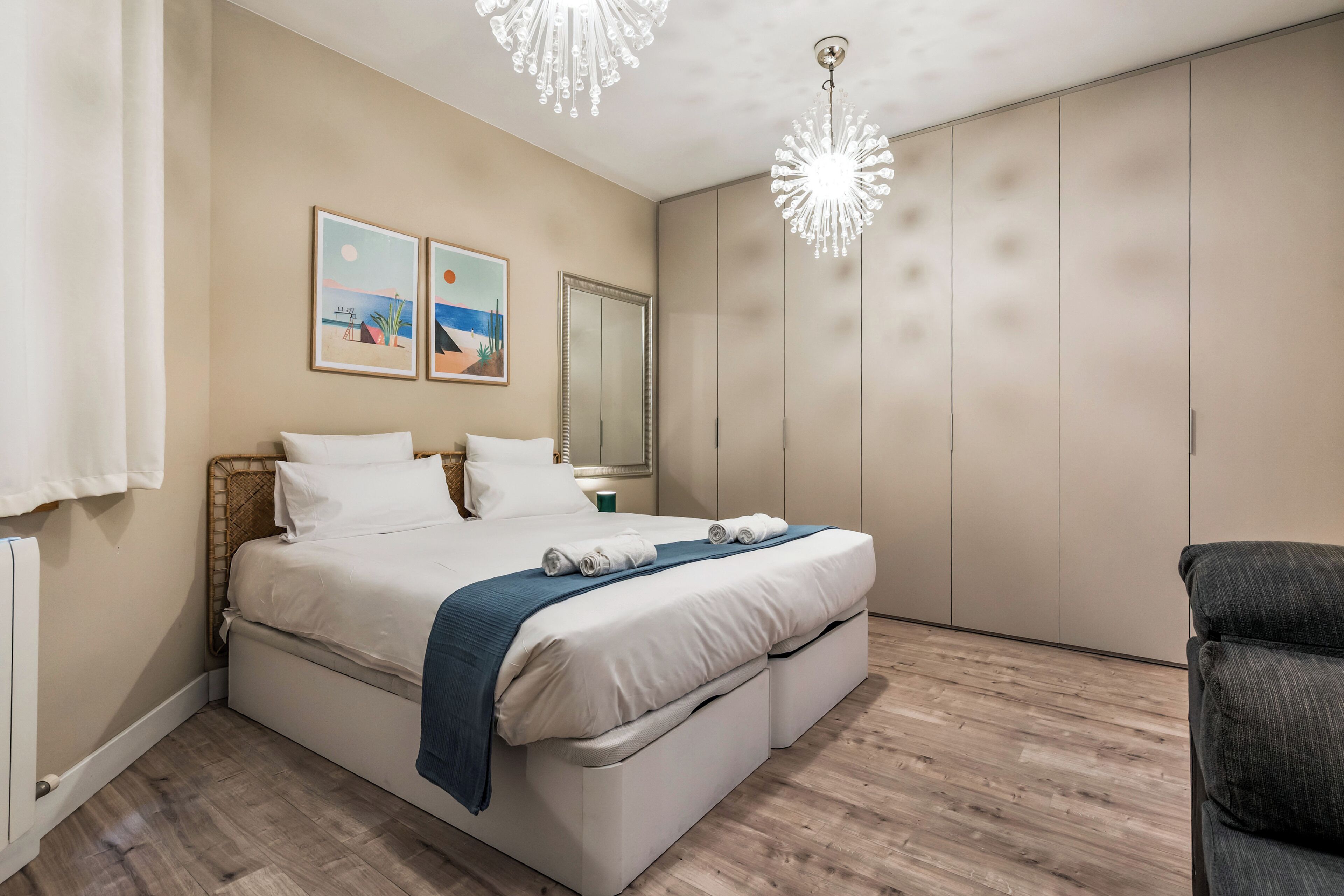 A bedroom with a bed, bedside tables, a wardrobe, and a chandelier.