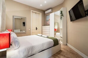 Ein Hotelzimmer mit Bett, Fernseher, Kleiderschrank, Spiegel und Klimaanlage.