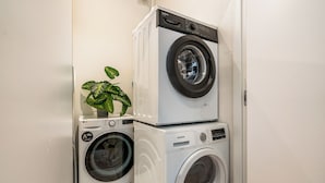 A laundry room with two stacked washing machines and a potted plant. - Modern, spacious monthly rental (min 32 nights) in the city centre. (Barcelona)
