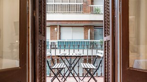 A view through a wooden door into a balcony with a table and chairs, a tiled floor, and a brick wall. - Modern, spacious monthly rental (min 32 nights) in the city centre. (Barcelona)