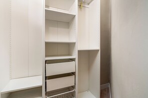 A white closet with multiple shelves and drawers, metal wire baskets, and a yellow tag on the door. - Modern, spacious monthly rental (min 32 nights) in the city centre. (Barcelona)