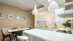 A modern kitchen with white cabinetry, a central island, and pendant lighting. - Modern, spacious monthly rental (min 32 nights) in the city centre. (Barcelona)
