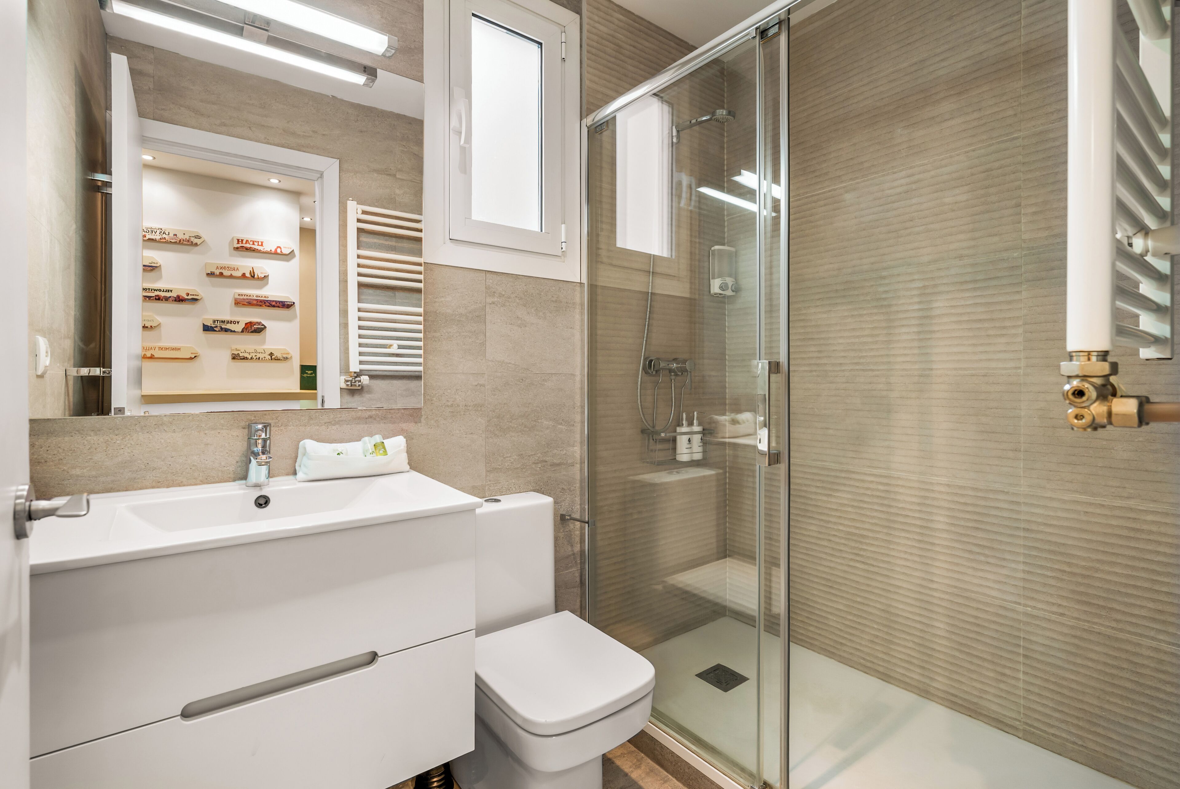 A modern bathroom with a glass shower enclosure, a white sink, and a toilet.