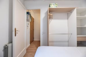Ein Schlafzimmer mit einem Bett, einem Kleiderschrank und einer kleinen Ablage mit einer Kiste.