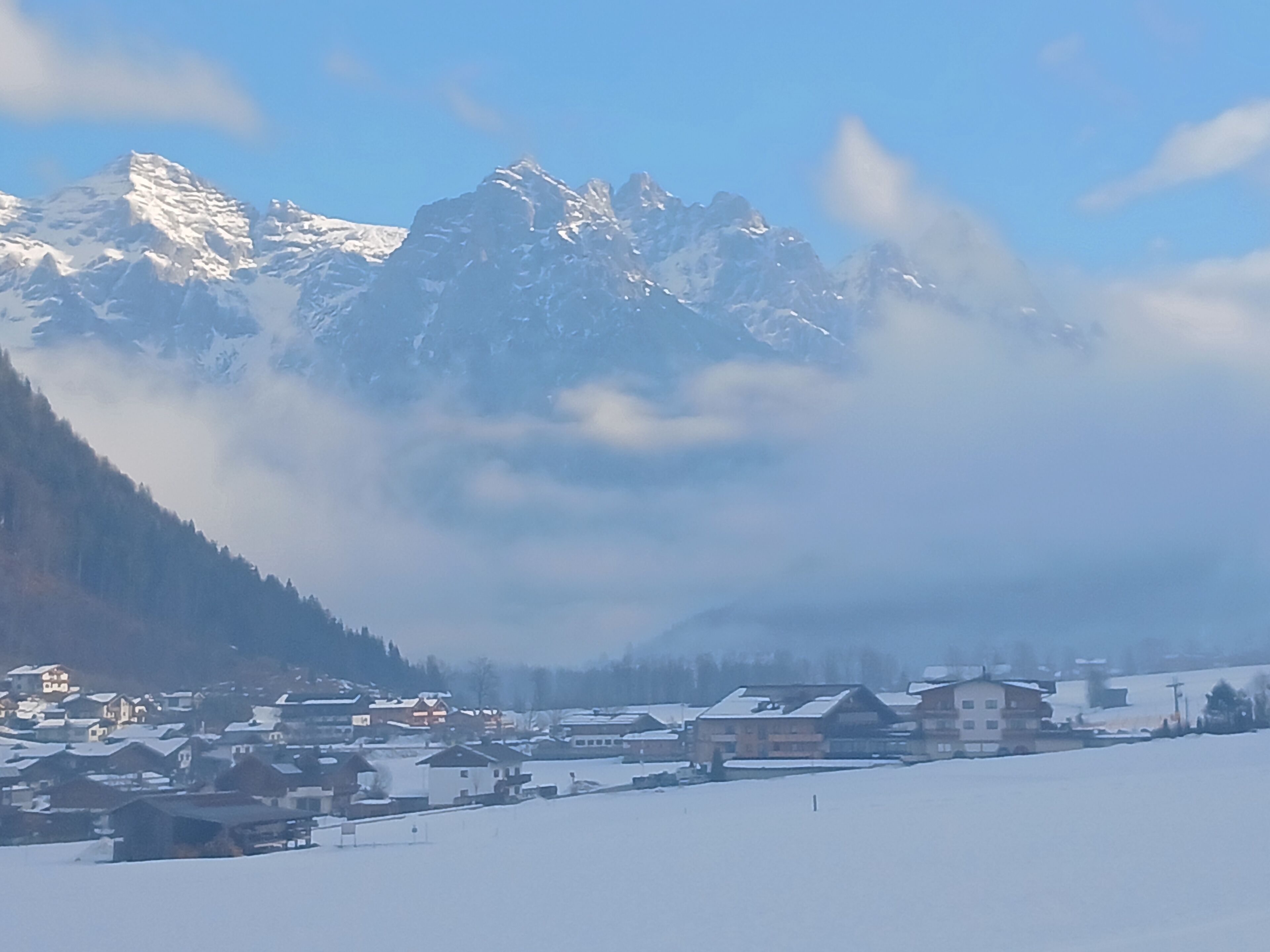 Ein verschneites Gebirge mit einem Dorf im Vordergrund.