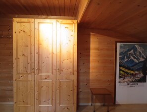 Ein Zimmer aus Holz mit einer Doppeltür, einem kleinen Tisch und einem Poster von den Alpen, Frankreich.