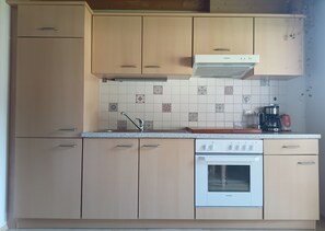 A kitchen with light-colored cabinets, a white stove, and a tiled backsplash.