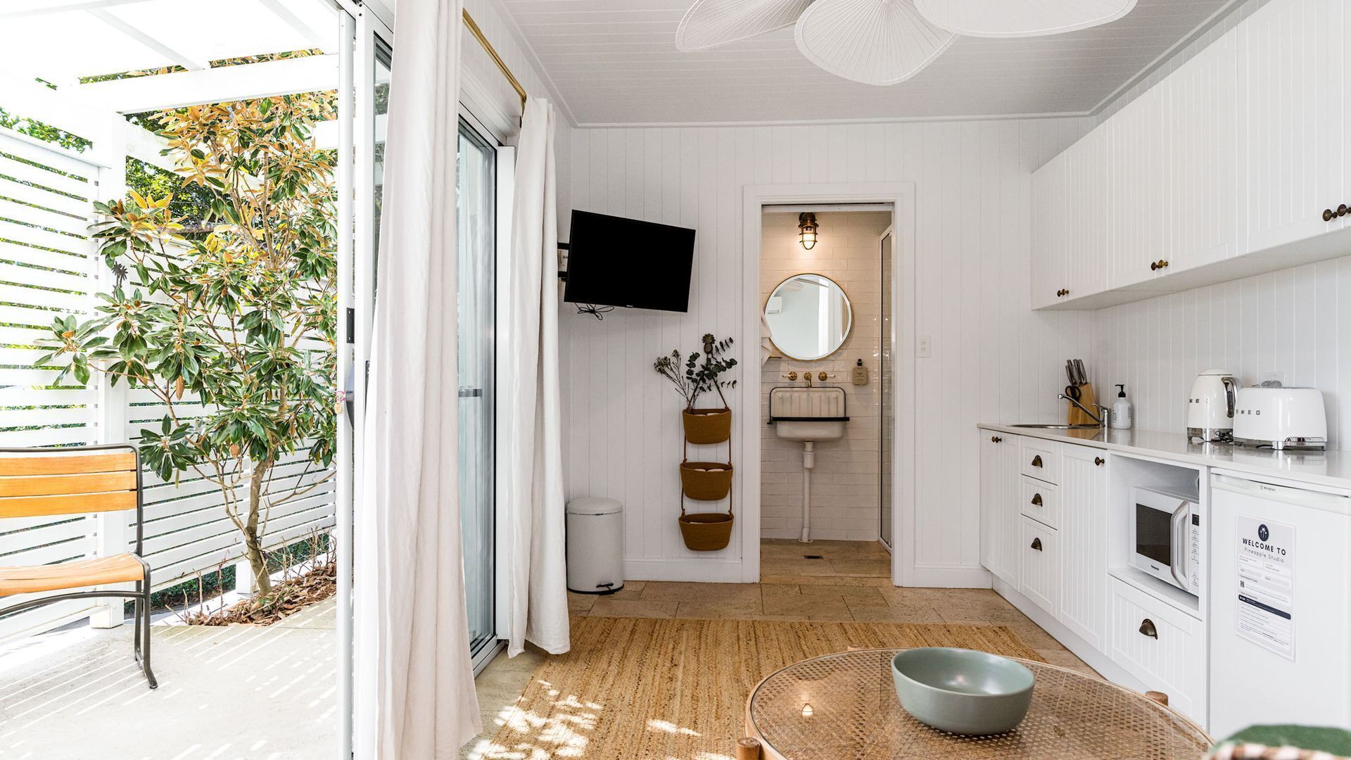 A modern kitchen with a built-in oven, a sink, and a flat-screen TV mounted on the wall.