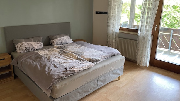 Un dormitorio con una cama, una mesita de noche y una ventana con cortinas.