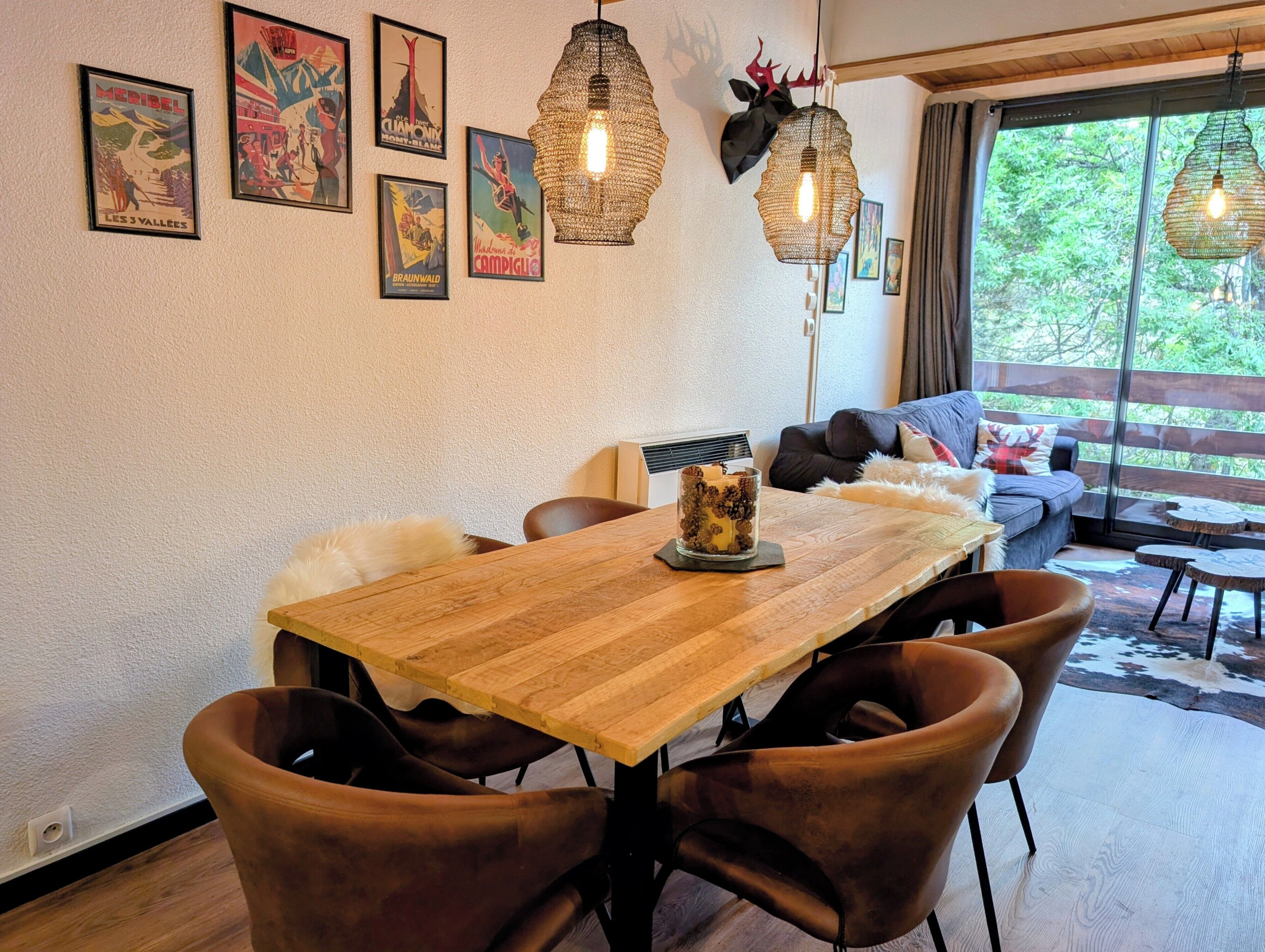 Un comedor con una mesa de madera, sillas marrones y un centro de mesa con velas.