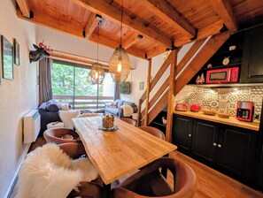 Ein gemütliches Blockhaus-Interieur mit einem Holzesstisch, rustikalen Einrichtungsgegenständen und einer Küchenzeile inklusive Mikrowelle.