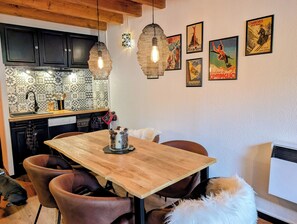 Eine moderne Küche mit einem gemusterten Rückwand, Pendelleuchten und einem Essbereich mit einem Holztisch und Ledersesseln.