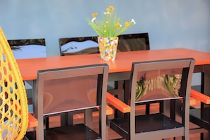 Ein Esstisch mit Stühlen, eine farbenfrohe Vase mit Blumen und ein gelber Sessel.