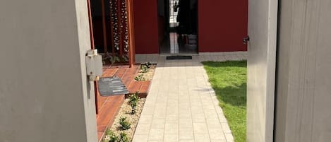 A pathway leading to a building with a red facade and a tiled roof.