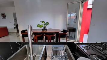 Une cuisine moderne dotée d’un évier en acier inoxydable, d’une cuisinière et d’un coin repas avec une table et des chaises.