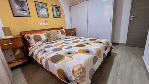 A bedroom with a bed, a wardrobe, a nightstand, and a wall with framed pictures. - Cité Italia - Quiet & elegant villa with garden/terrace - near the beaches (Modest)