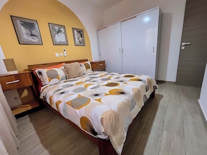 A bedroom with a bed, a wardrobe, a nightstand, and a wall with framed pictures. - Cité Italia - Quiet & elegant villa with garden/terrace - near the beaches (Modest)