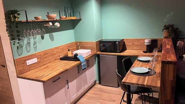 A modern kitchen with wooden countertops, a built-in microwave, a sink, and a small refrigerator.