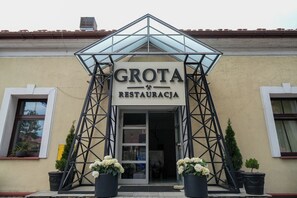 A building with a sign reading 'GROTA RESTAURACJA' and a triangular metal structure above the entrance. - Hotel Sutoris (Bochnia)